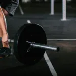 Buty do CrossFitu z płaską, twardą podeszwą przy sztandze na gumowej podłodze boxu