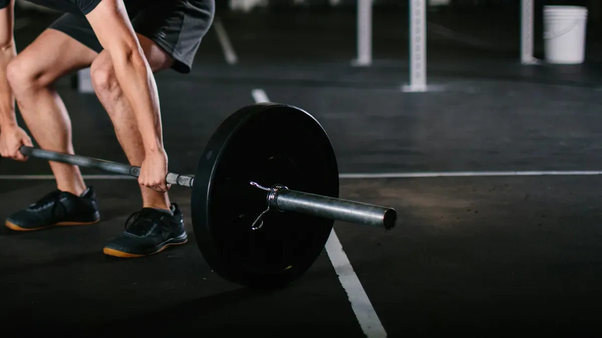Buty do CrossFitu z płaską, twardą podeszwą przy sztandze na gumowej podłodze boxu