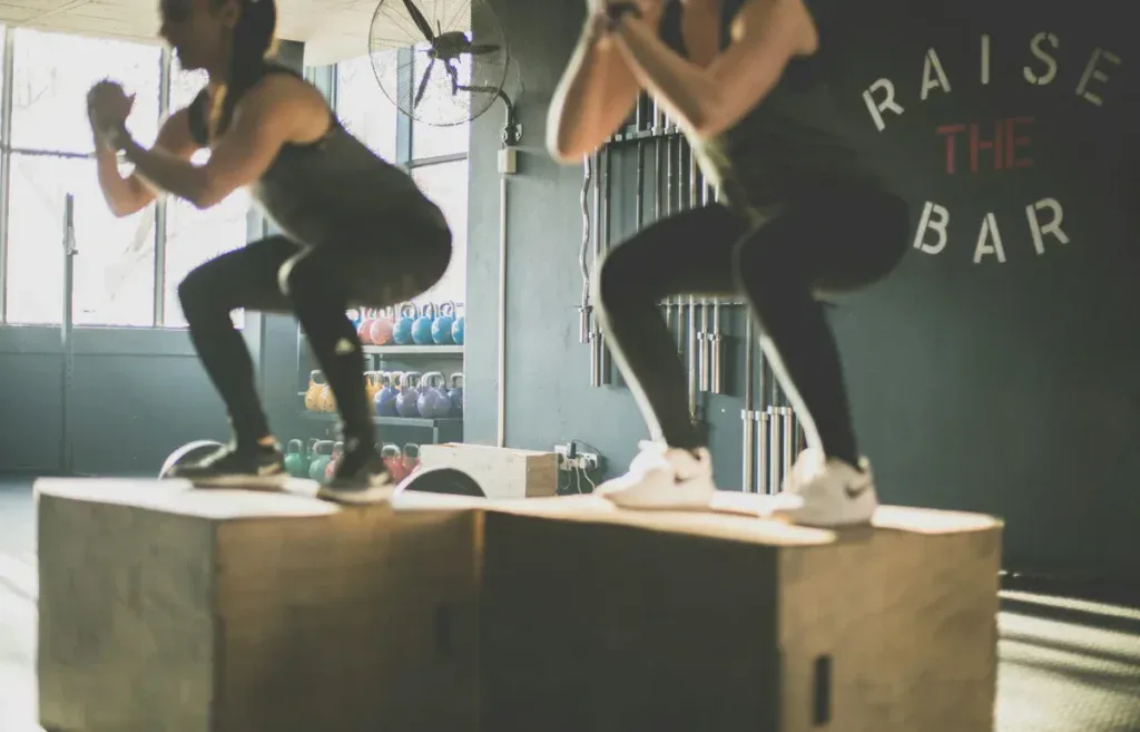 Dwie zawodniczki trenują obok siebie na skrzyniach, trening w parze przed startem w Doubles